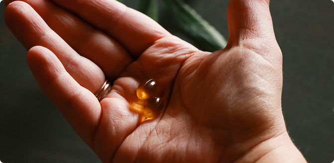 Hand holding two transparent supplement capsules, natural wellness concept