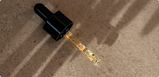 CBD oil dropper with clear liquid on a stone surface, wellness and supplement concept