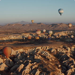 Hot air balloons floating over a rocky landscape at sunrise, clear blue sky