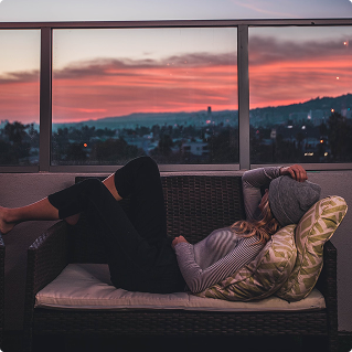 Woman relaxing on outdoor sofa at sunset, peaceful evening atmosphere, wellness lifestyle
